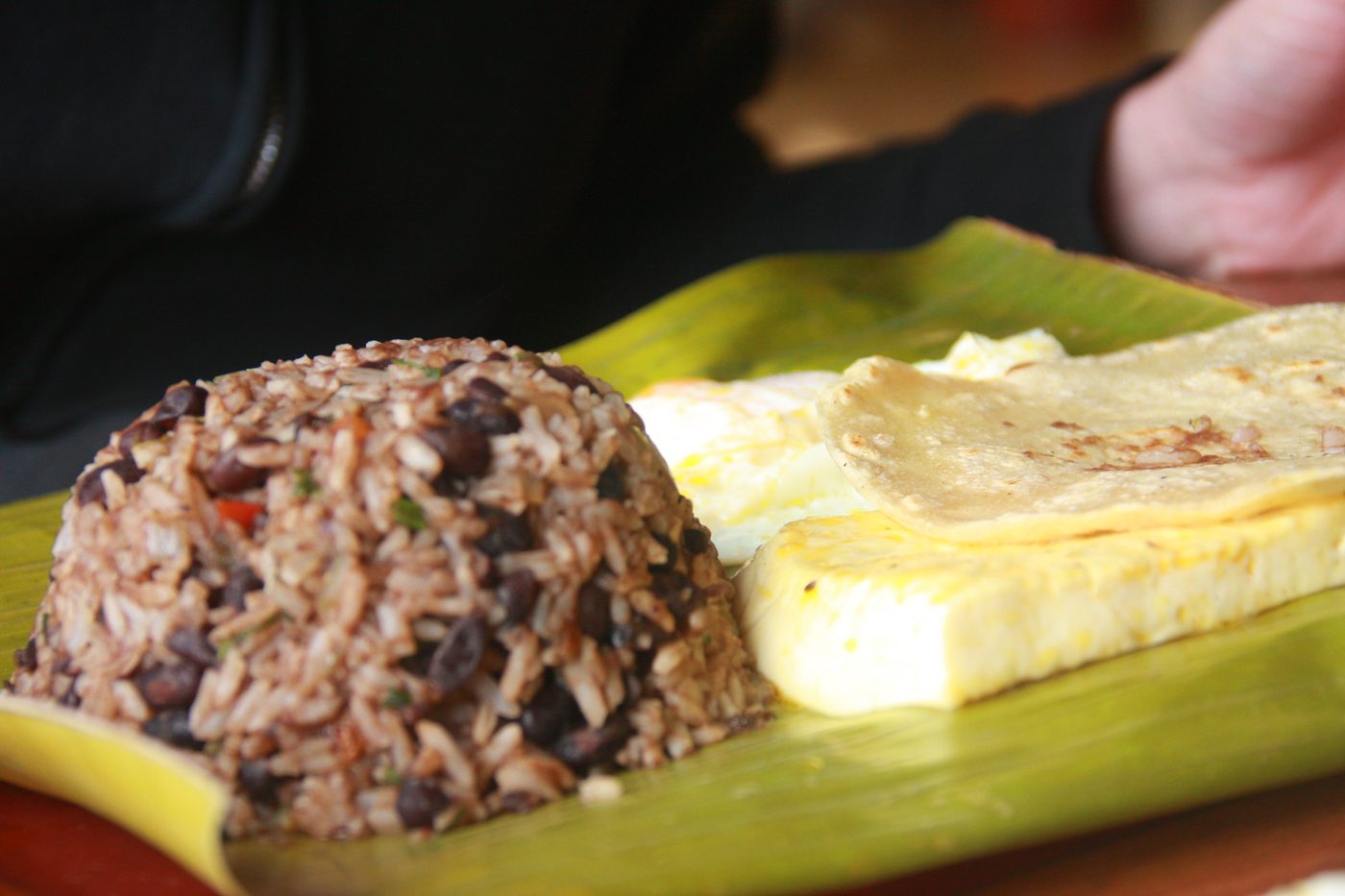 Gallo pinto with eggs, cheese, and tortilla served on a banana leaf